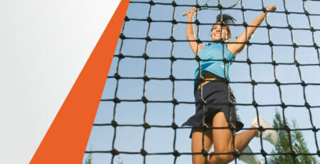 A Woman with Tennis Racket Behind the Net Jumps Up