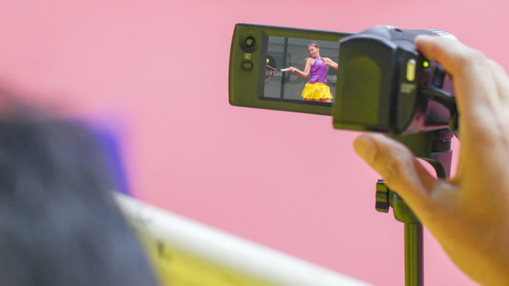 Filming a girl playing tennis with a camera to get tennis tips from coaches.